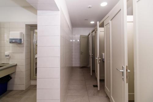 a bathroom with white tile walls and a hallway with stalls at Motel "Tri lovca" in Knin