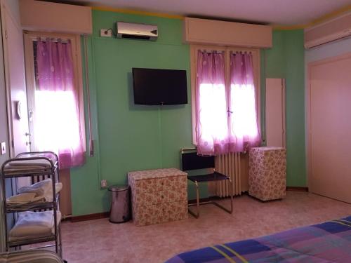 a bedroom with green walls and pink curtains and a tv at Bed And Breakfast Adrj in Cavriago