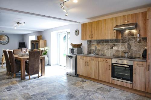 uma cozinha com armários de madeira e uma mesa com cadeiras em L'anerie de Sourbrodt em Sourbrodt