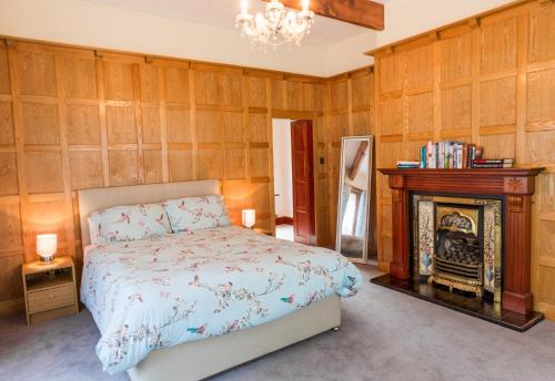 1 dormitorio con 1 cama y chimenea en Highwood Lodge en Scissett