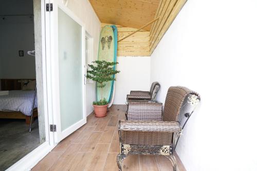 a porch with two chairs and a surfboard on the wall at The Red Hotel in Nanwan
