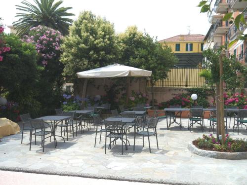 a group of tables and chairs with an umbrella at Hotel Flora in Celle Ligure
