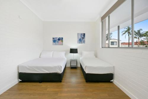two beds in a white room with two windows at Australian Community Villages in Bankstown