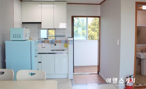 a kitchen with white cabinets and a white refrigerator at Toursketch Pension in Seogwipo