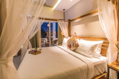 a bedroom with a bed with white sheets and a window at Swosti Chilika Resort in Kānāipur