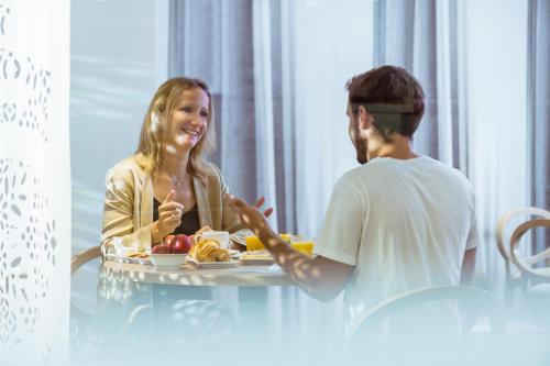 a man and a woman sitting at a table with a plate of food at Mercure Toulouse Centre Wilson Capitole in Toulouse