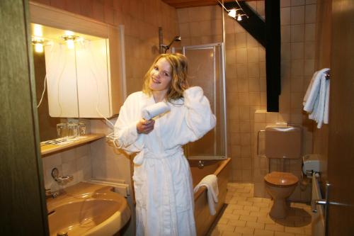 a woman standing in a bathroom holding a hair dryer at AKZENT Hotel Stadt Bremen in Beverungen