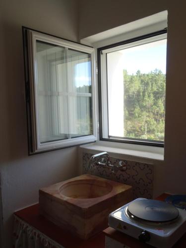 a bathroom with a wooden sink and two windows at Palheiros da Ribeira in Pracana Cimeira