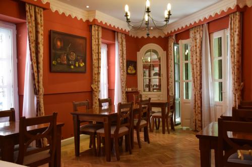 uma sala de jantar com paredes cor de laranja e mesas e cadeiras de madeira em Posada Don Jaime em San Lorenzo de El Escorial