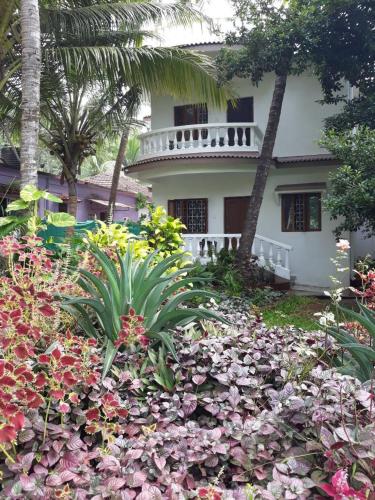 a house with a flower garden in front of it at Agnelo's Holiday Homes in Candolim