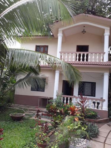a house with a palm tree in front of it at Agnelo's Holiday Homes in Candolim