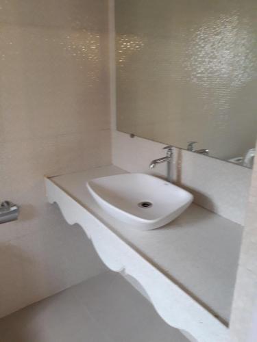 a white bathroom with a sink and a mirror at Agnelo's Holiday Homes in Candolim
