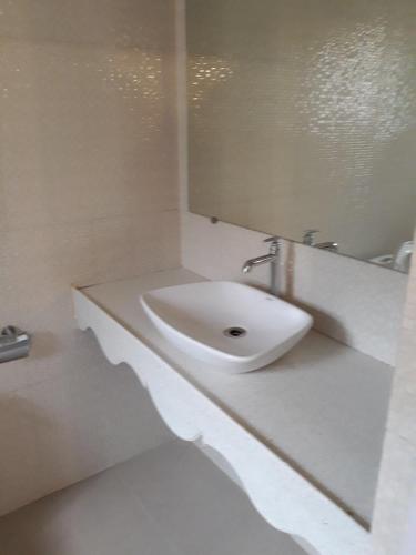 Baño blanco con lavabo y espejo en Agnelo's Holiday Homes, en Candolim