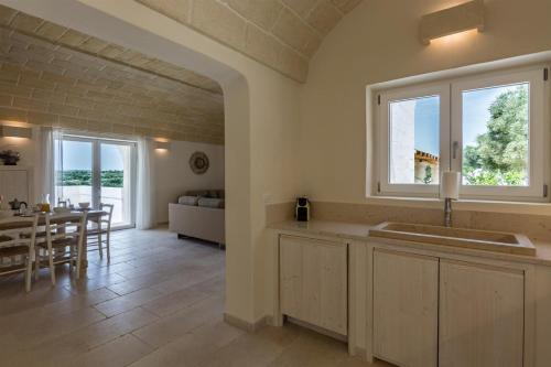 kuchnia i jadalnia ze stołem i oknem w obiekcie La Residenza - Corte dei Messapi Raro Villas Collection w mieście Ostuni