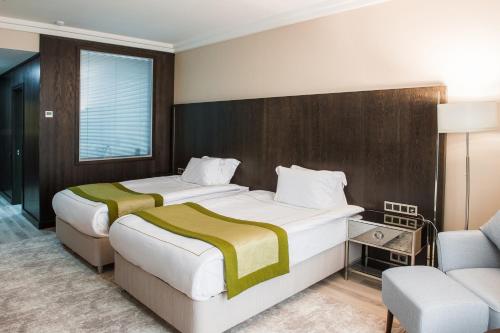a hotel room with two beds and a chair at The ONE Hotel Astana in Astana