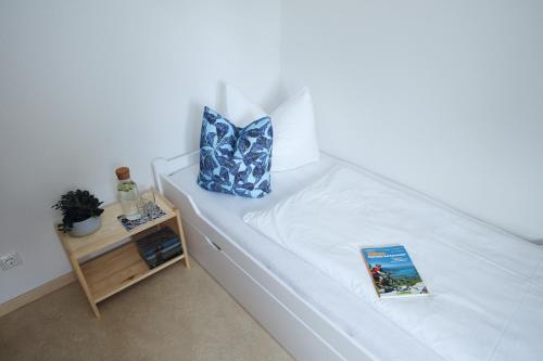 a book sitting on a bed with a pillow and a table at Berg Blick Jugendherberge mit Privatzimmer in Kochel