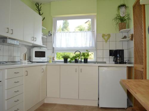 een keuken met witte kasten en een raam bij Ferienhaus Ritzhaupt in Angelbachtal