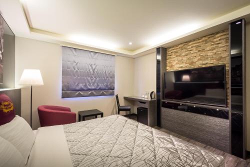 a hotel room with a bed and a flat screen tv at Carnival Motel in Taipei