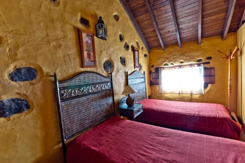 a bedroom with two beds in a stone wall at Casa Rural Poblado Jirdana in La Torre