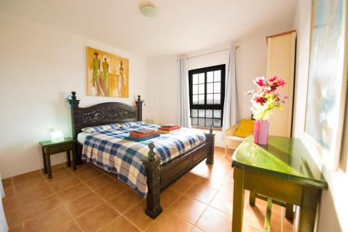a bedroom with a bed and a table and a desk at VillaTommy heated pool, hottub, fast wifi in Lajares