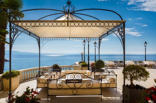 a bed in a gazebo with the ocean in the background at Hotel Kvarner - Liburnia in Opatija