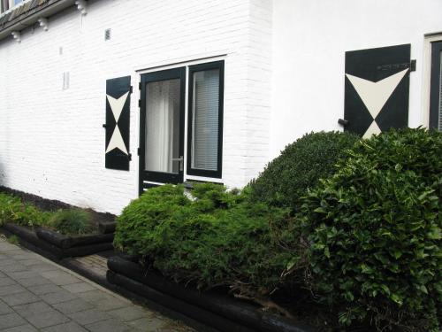 a white house with black doors and green bushes at B&B Texels Groen in Oudeschild