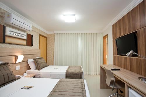 a hotel room with two beds and a television at Bristol Jaraguá Hotel Pampulha in Belo Horizonte