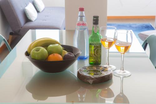 a glass table with a bowl of fruit and two wine glasses at Five Design Rooftop by Storytellers in Funchal
