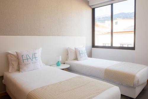 two beds in a room with a window at Five Design Rooftop by Storytellers in Funchal