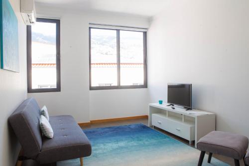 a living room with a chair and a tv at Five Design Rooftop by Storytellers in Funchal