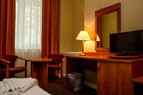 a hotel room with a desk with a television and a mirror at Hotel Astrid am Kurfürstendamm in Berlin