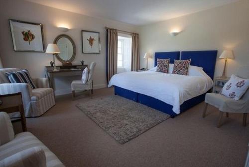 a bedroom with a bed and a chair and a mirror at Bridgend Hotel in Bridgend