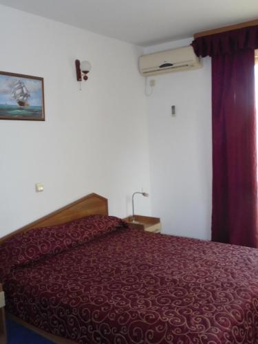 a bedroom with a bed with a red bedspread at Byala Perla Family Hotel in Byala