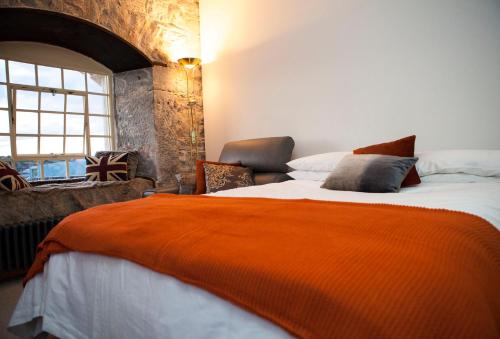 een slaapkamer met een groot bed en een oranje deken bij Mayflower Apartments, Royal William Yard in Plymouth