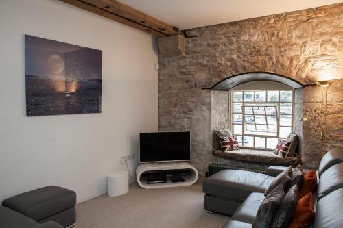 a living room with a stone wall and a tv at Mayflower Apartments, Royal William Yard in Plymouth