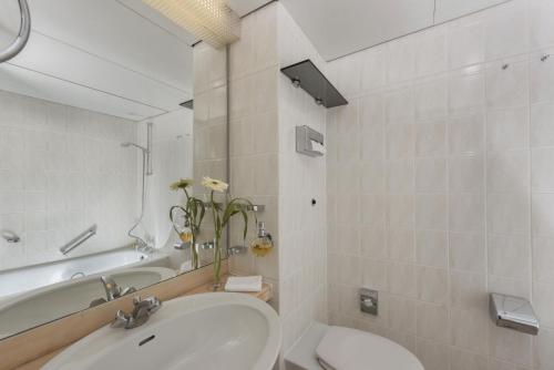 a bathroom with a sink and a tub and a toilet at Maritim Hotel Bad Salzuflen in Bad Salzuflen