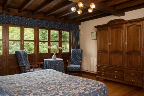 um quarto com uma cama, 2 cadeiras e uma cómoda em Casa Rural La Regoria em Carreña de Cabrales