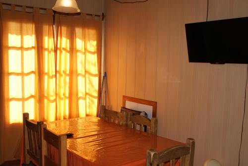a dining room with a wooden table and a television at El Puente Aparts- Departamentos Independientes in El Calafate