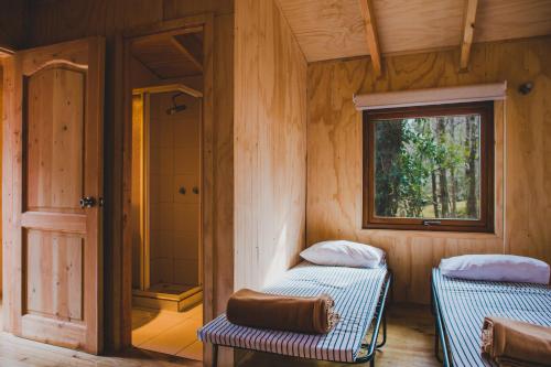 a bathroom with two beds and a shower in a room at Huilo Huilo Canopy Village in Huilo Huilo