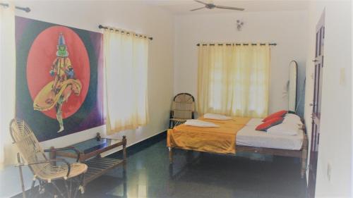 a bedroom with a bed and two chairs and a painting at Indian Art Villa in Varkala