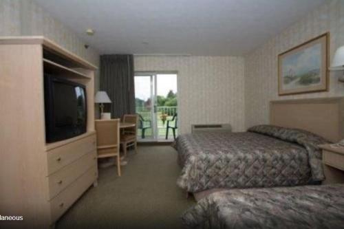 a hotel room with two beds and a flat screen tv at Winnapaug Inn in Westerly