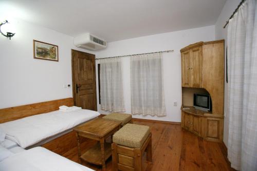 a bedroom with two beds and a table and a tv at Guest House The Old Lovech in Lovech