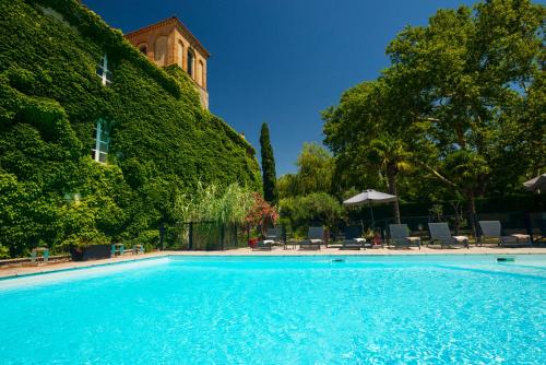 a swimming pool with chairs and a building at Le Domaine Du Colombier in Malataverne