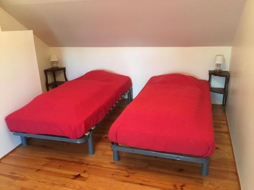 2 Betten in einem Zimmer mit roter Bettwäsche in der Unterkunft Maison la Quentinière in Saint-Calais-du-Désert