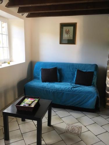 a blue couch in a living room with a table at Maison la Quentinière in Saint-Calais-du-Désert