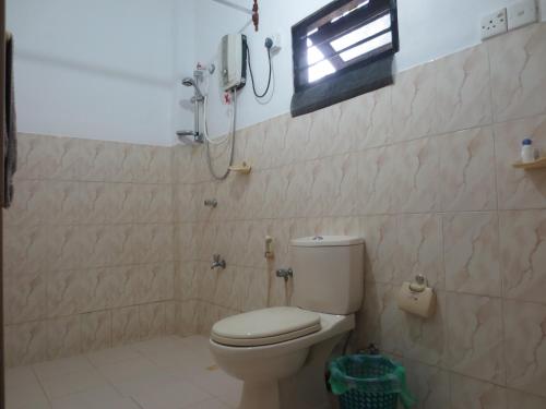 a bathroom with a toilet and a phone on the wall at Jungle Holiday Home in Hikkaduwa