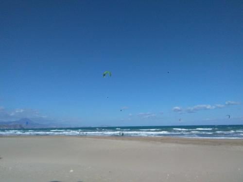 a person is flying a kite on the beach at Al Andalus, Playa de Muchavista in El Campello