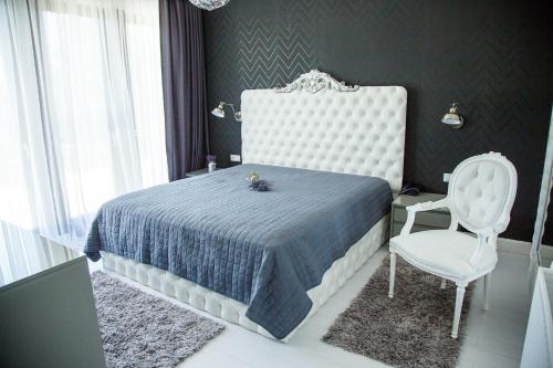 a bedroom with a bed and a white chair at Pensiunea Primaverii in Satu Mare