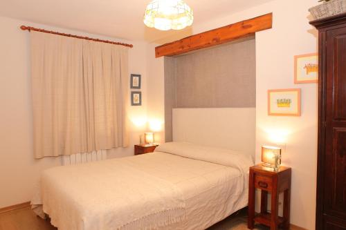 a bedroom with a white bed and two night stands at Apartamentos Albá Casa Alquesera in Sahun