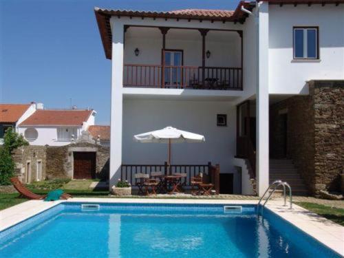 a house with a swimming pool and an umbrella at Solar do Morgado Oliveira in Macedo de Cavaleiros